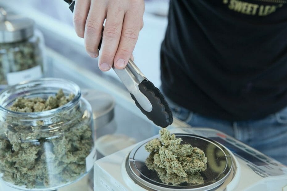 person weighing cannabis with a jar in the background